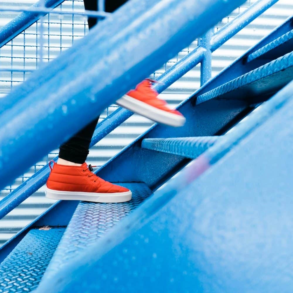 a person going up stairs with red shoes